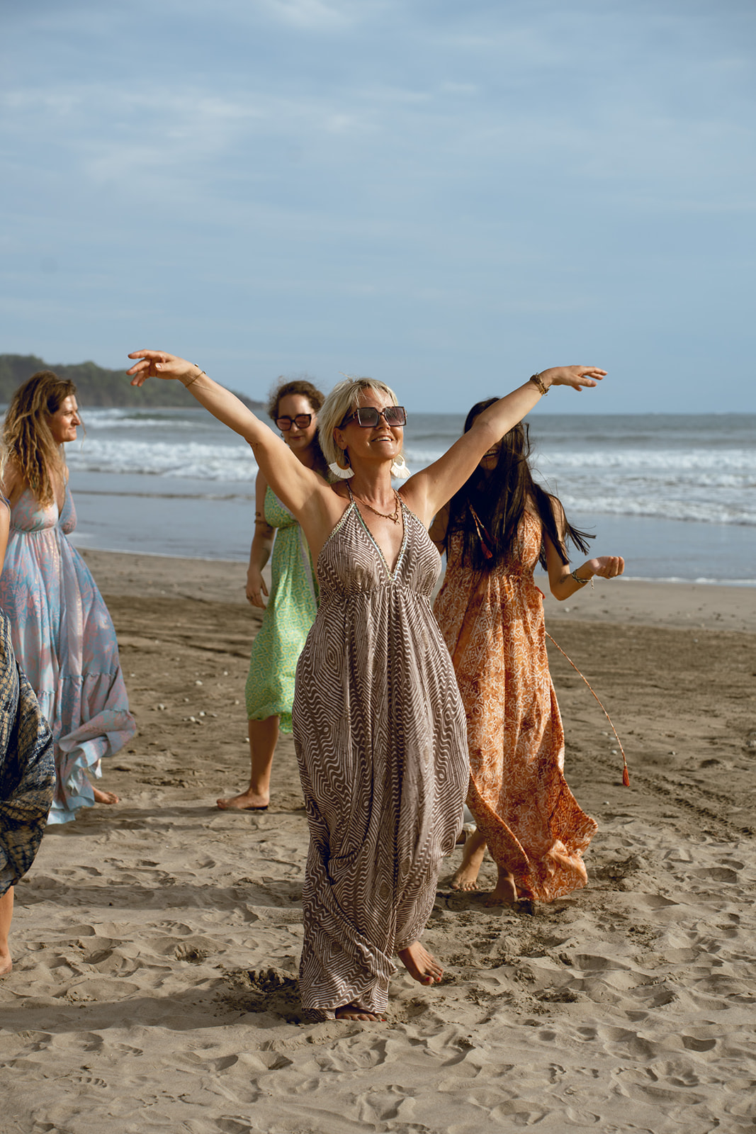 Frauen tanzen frei und mit erhobenen Armen am Strand