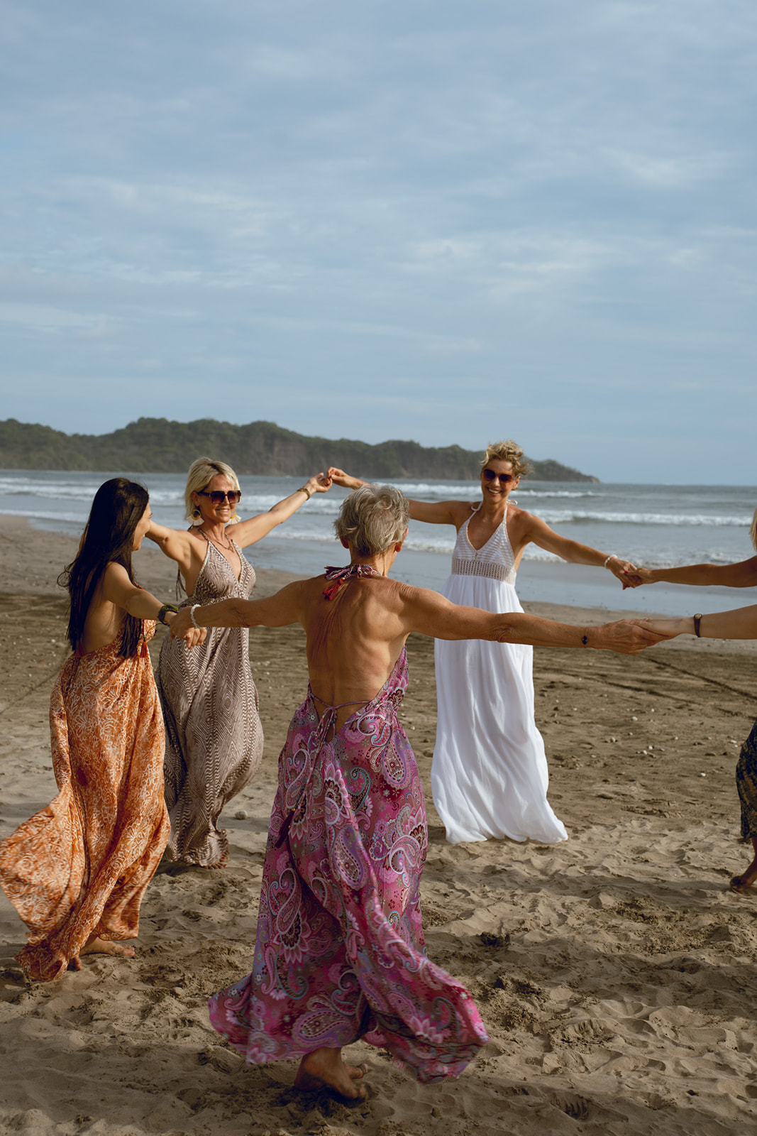 Frauen tanzen im Kreis am Strand